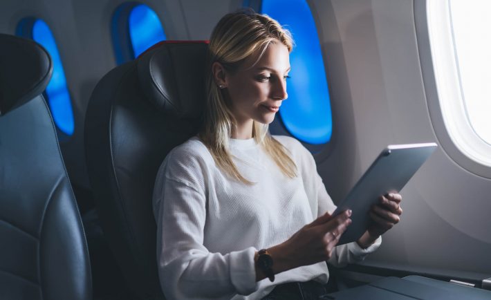 Kobieta w samolocie z technologią elektrochromową i tabletem
