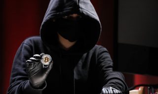 przestępca ubrany na czarno kradnący bitcoina