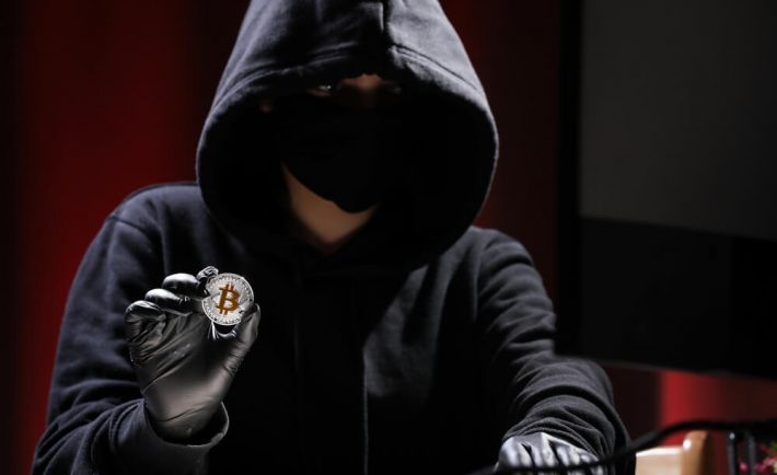 przestępca ubrany na czarno kradnący bitcoina
