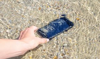Telefon leżący pod wodą, na piasku.